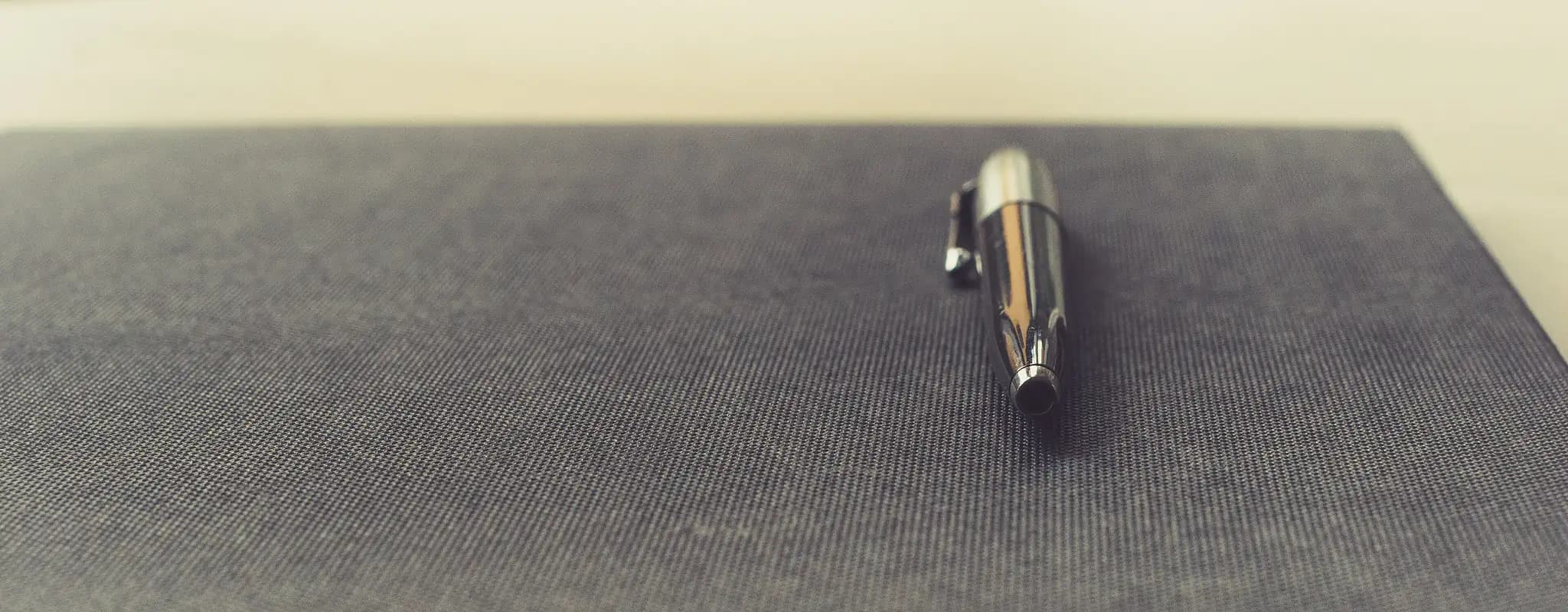 A black planning notebook with a pen resting on its cover.