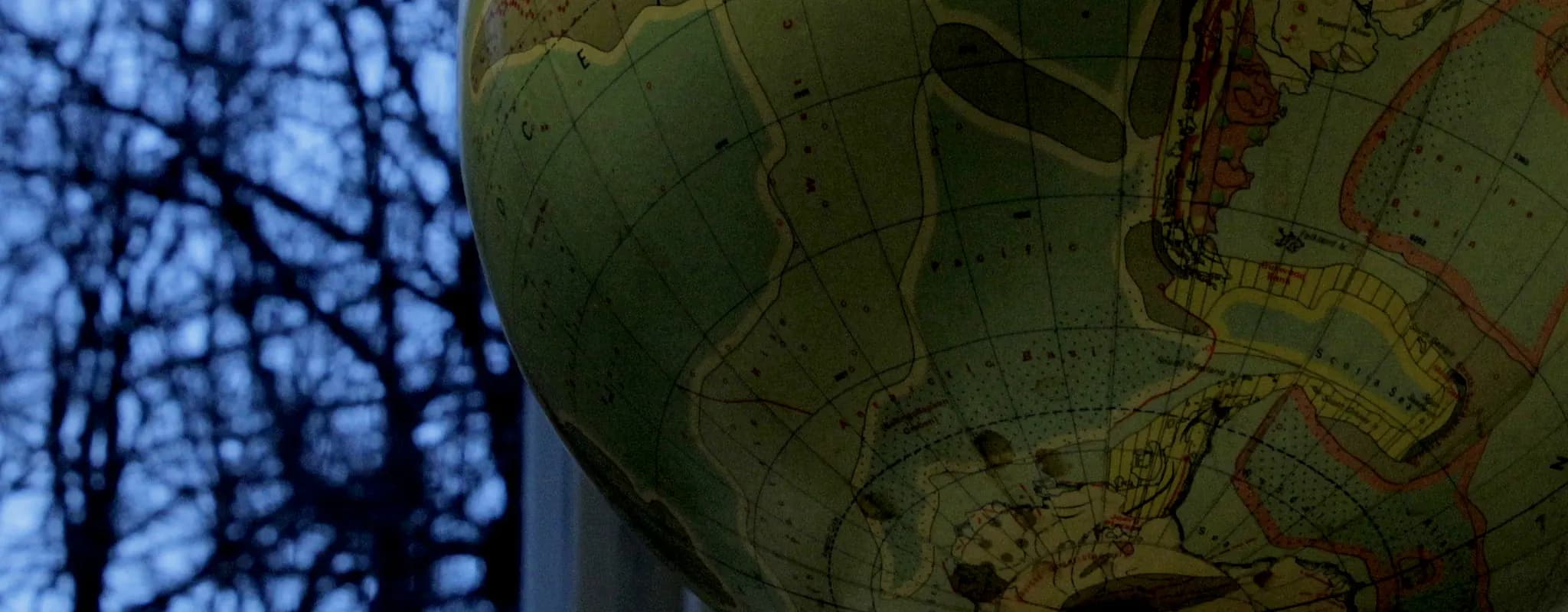 Close-up of a globe lit from the side against a blue background.