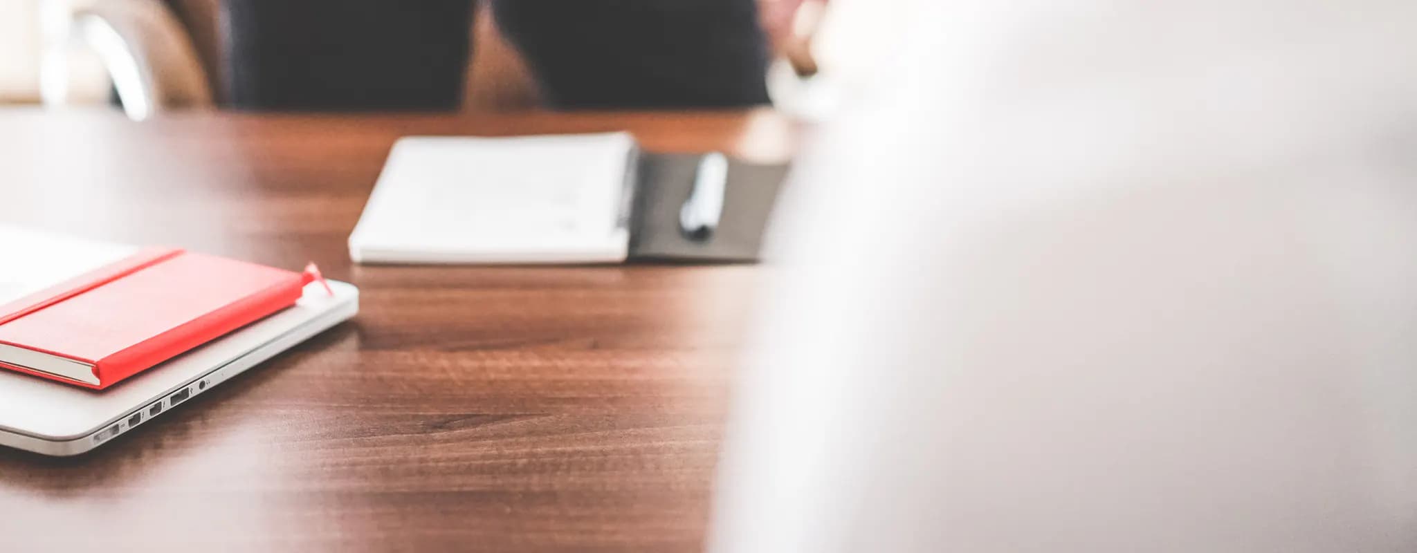 Two businesspeople shake hands across an office desk after reaching an agreement.