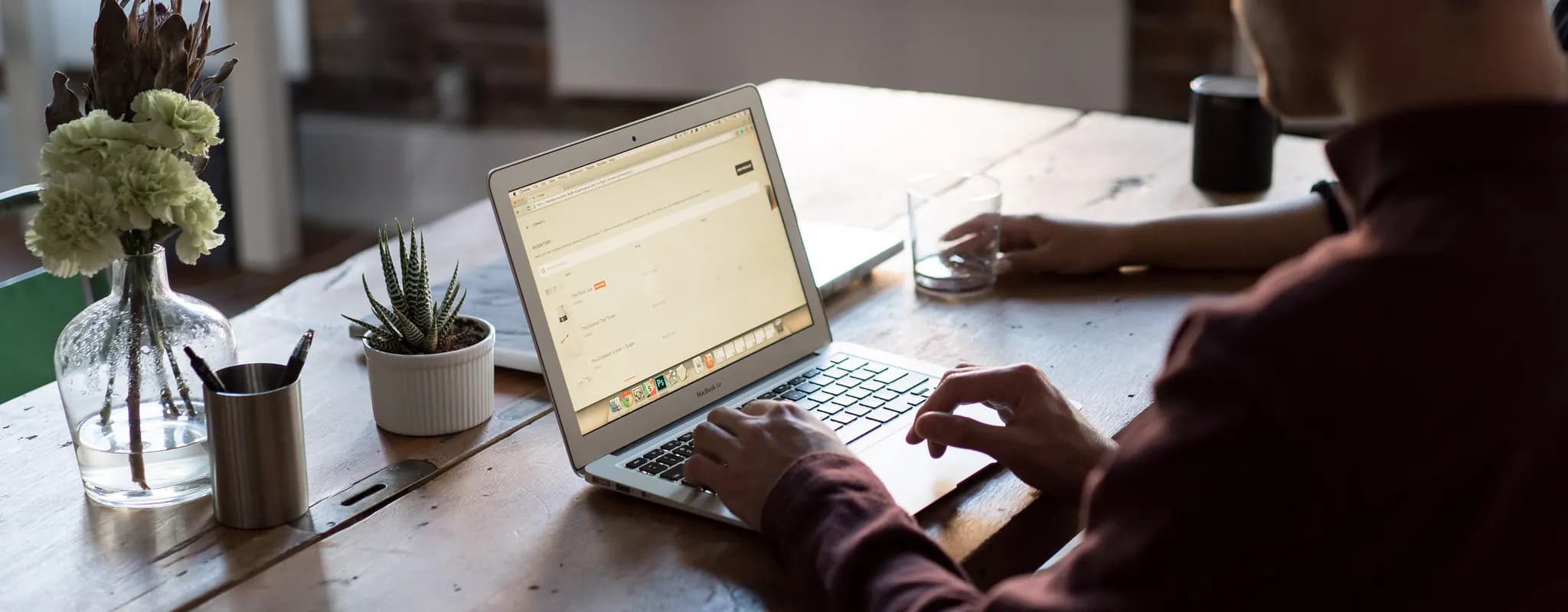 A professional works on a laptop at a wooden table in a modern office.