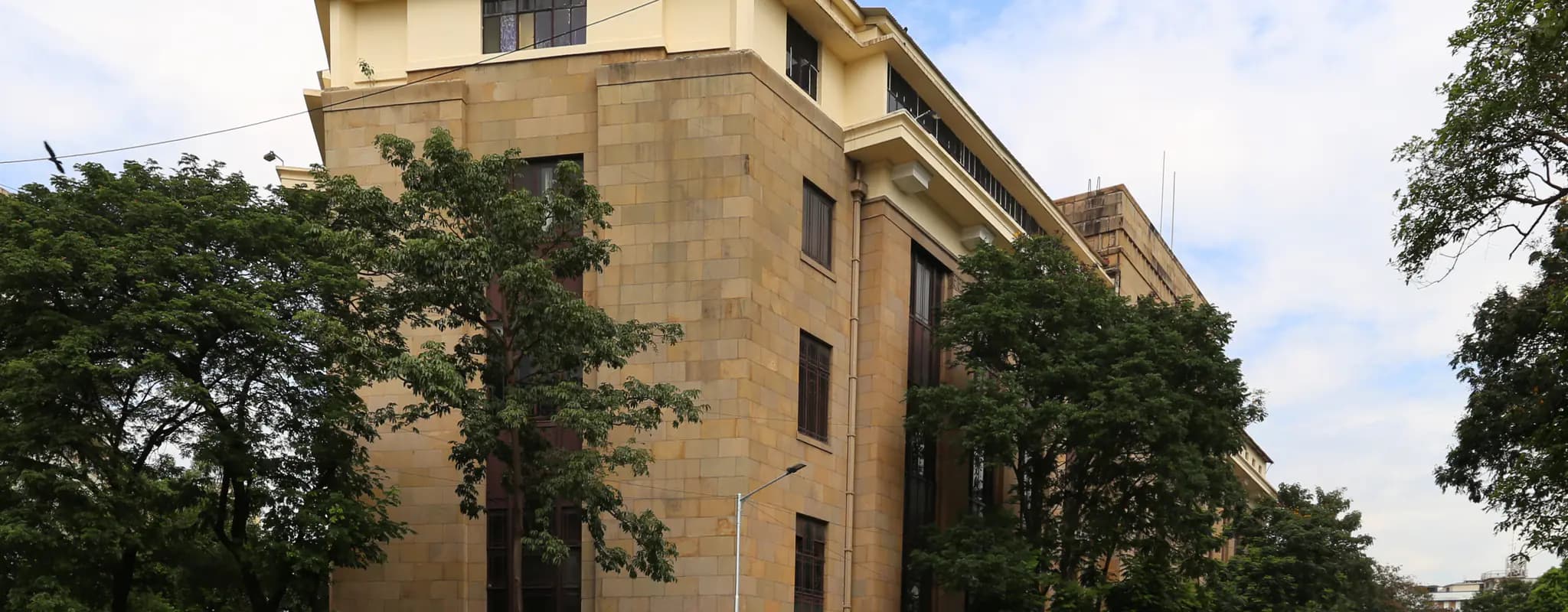 The Reserve Bank of India building on a tree-lined Mumbai street.