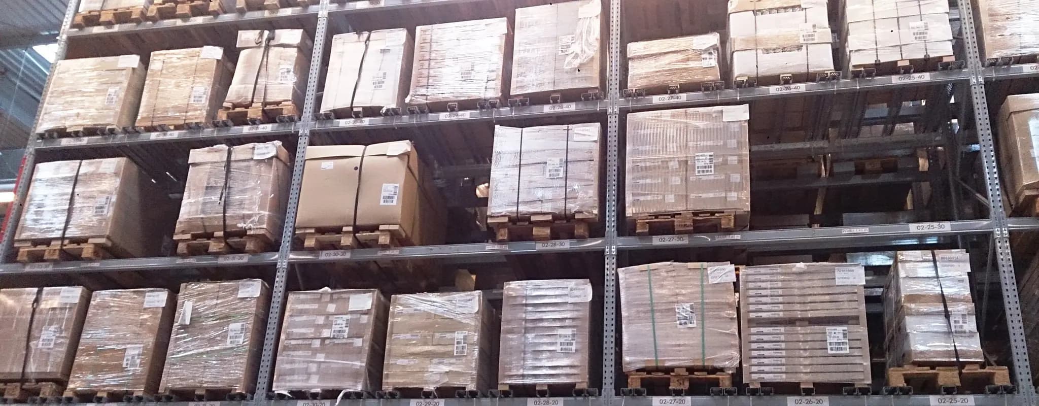 Rows of shrink-wrapped goods stacked on tall warehouse racks.