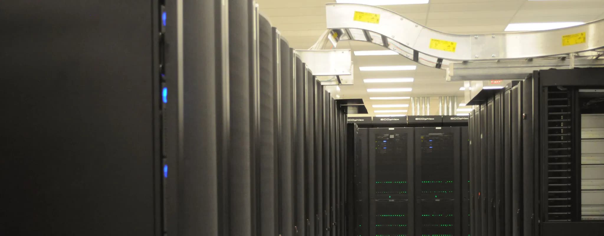 An aisle lined with tall black server racks and glowing status lights.