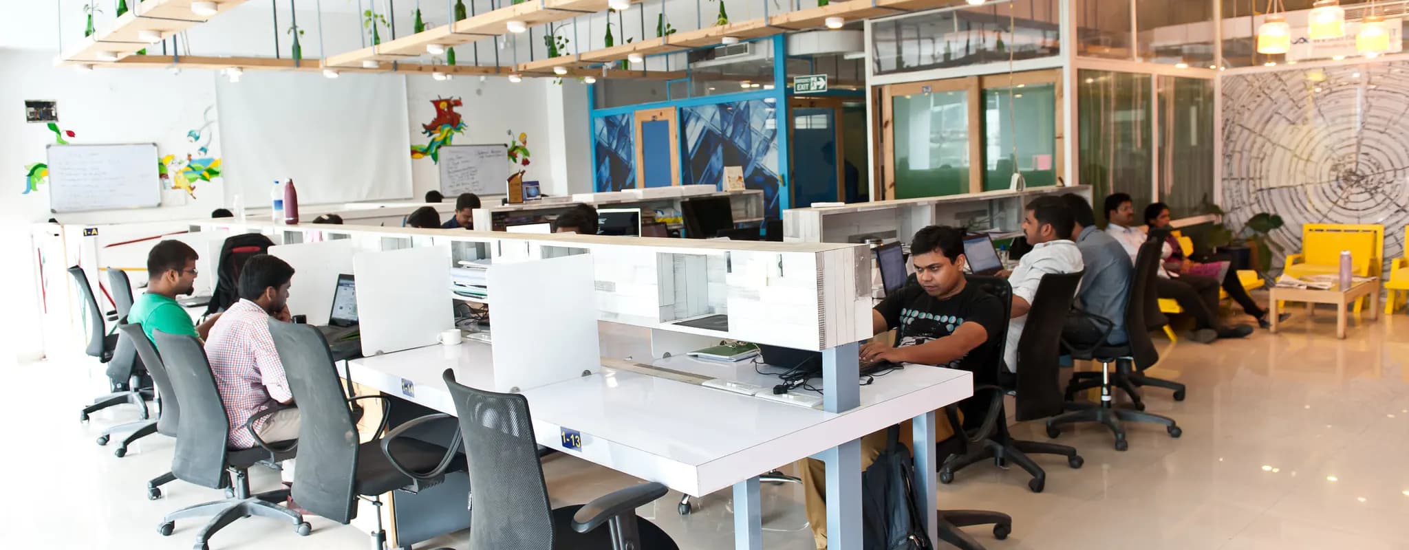 Professionals work at computers in a bright Bengaluru coworking office.