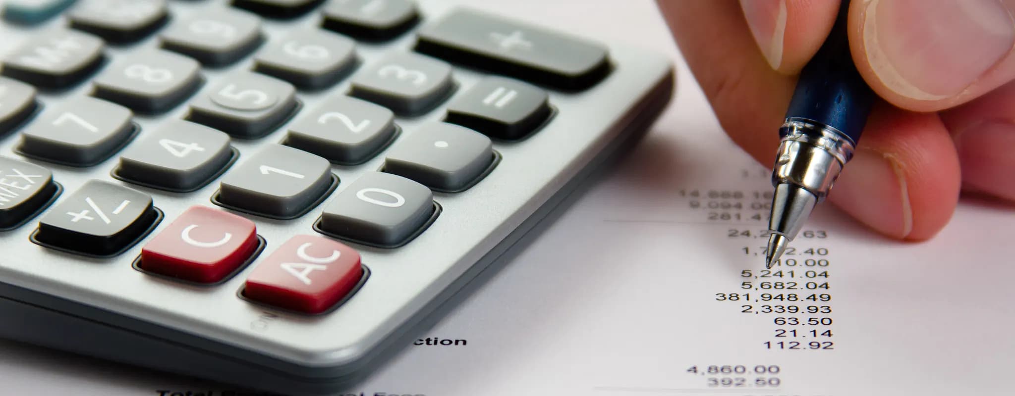 A hand uses a calculator and pen over a printed financial statement.