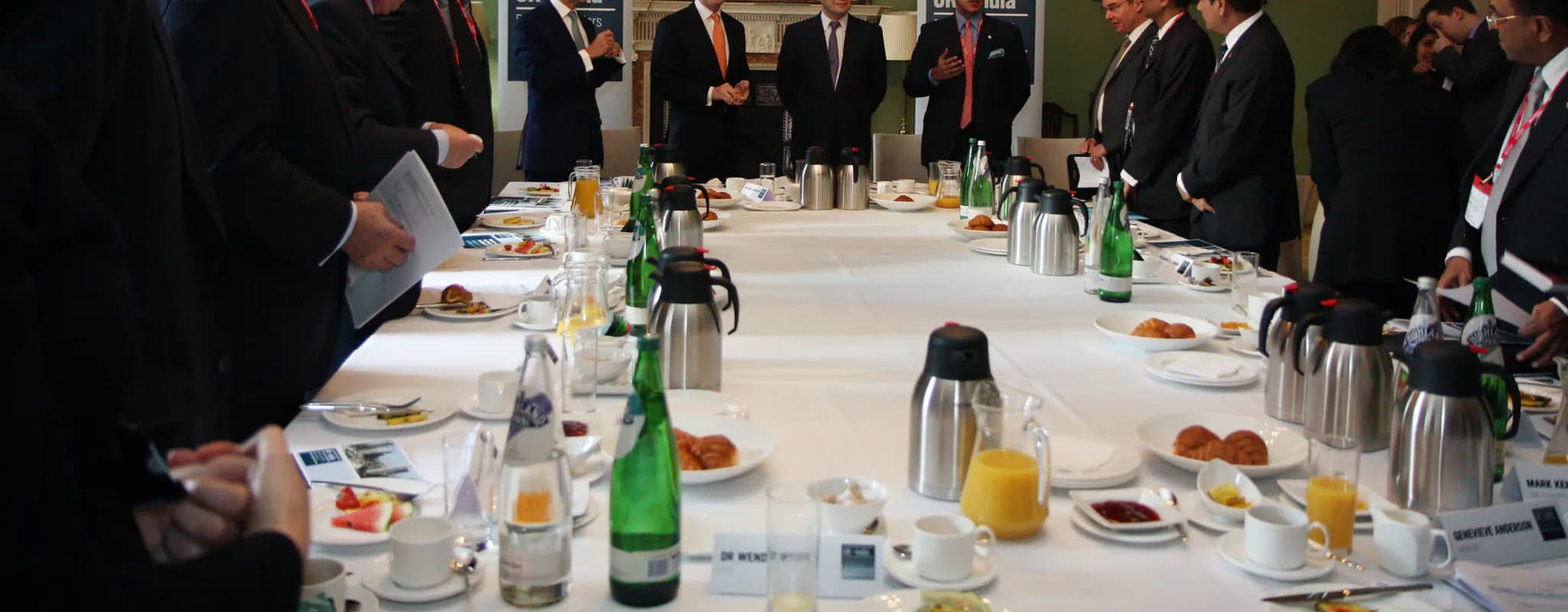 Indian and British business leaders stand around a long conference table during a joint working meeting.