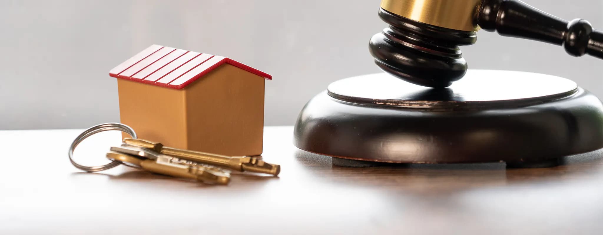 House keys and a model home are arranged beside a wooden gavel.