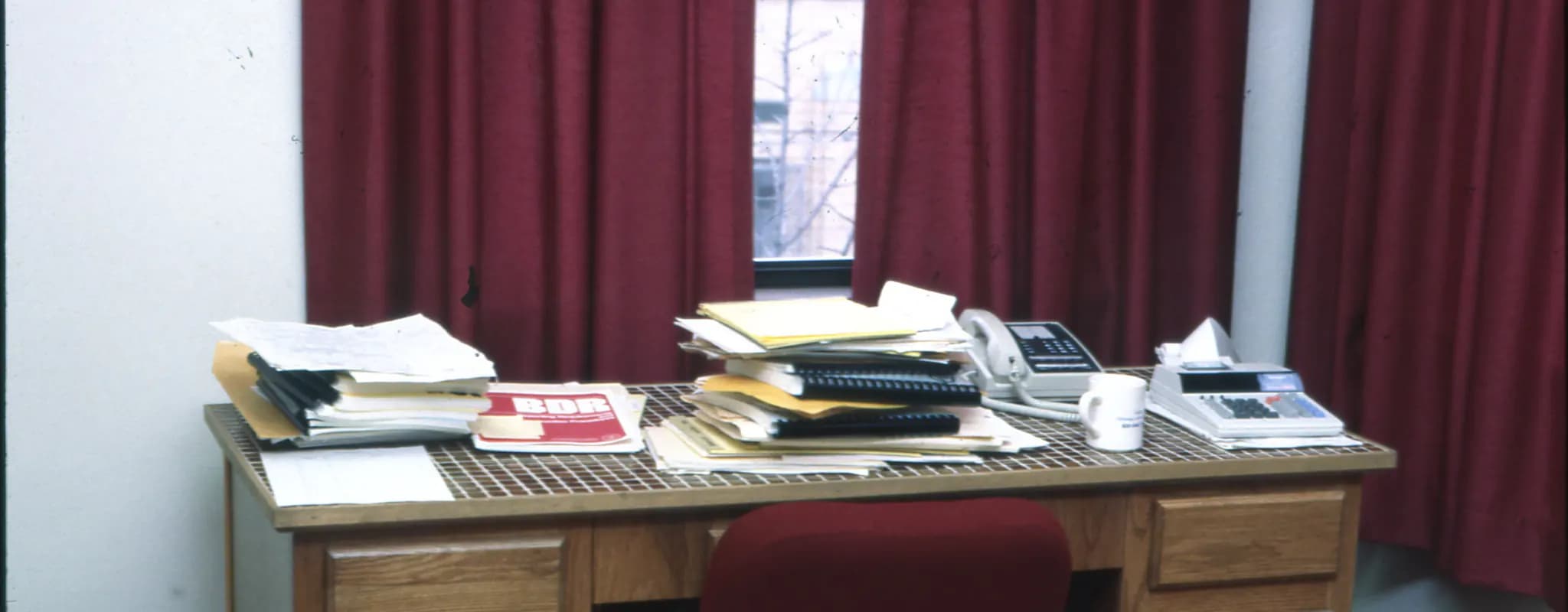 An office desk arranged with stacks of financial papers, a calculator and a telephone.