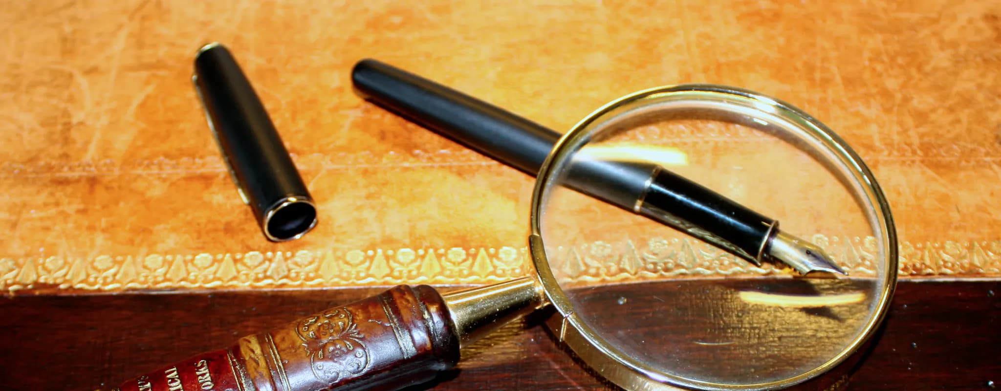 A magnifying glass and fountain pen are arranged on a document case.