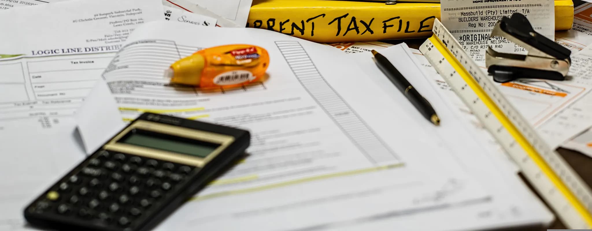 A calculator, pen and paperwork are arranged for an income-tax calculation.