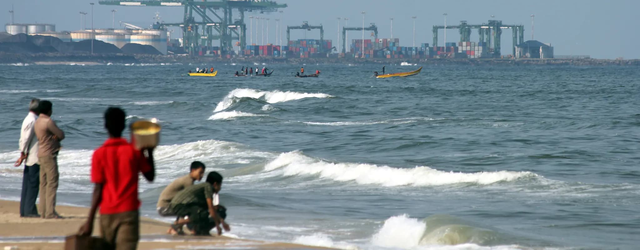 Container cranes and stacked freight at Chennai Port seen across the shoreline.