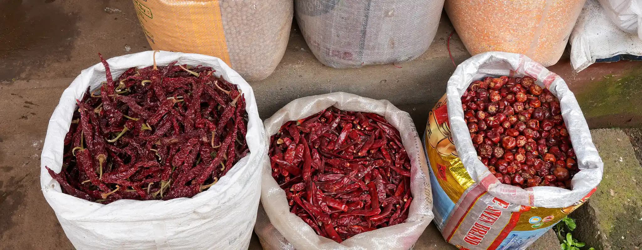 Open sacks of pulses, grains and dried red chillies displayed at Ooty Municipal Market.