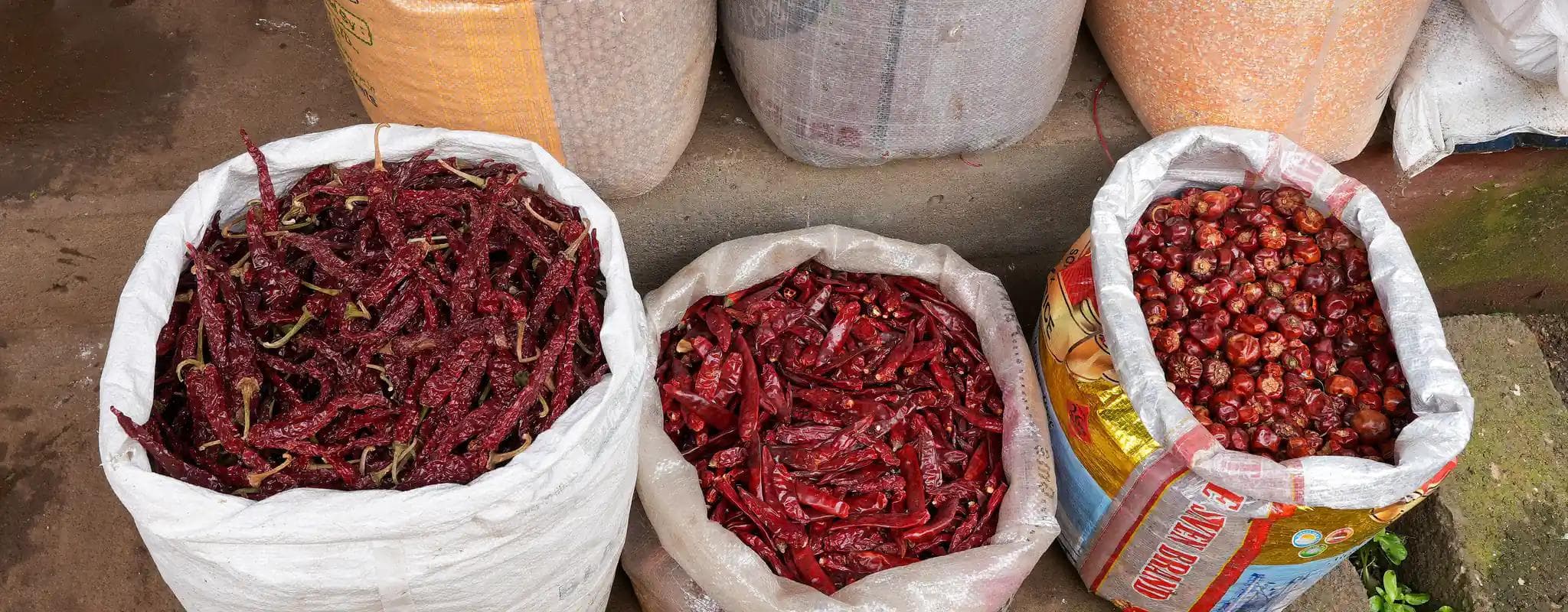Open sacks of pulses, grains and dried red chillies displayed at Ooty Municipal Market.