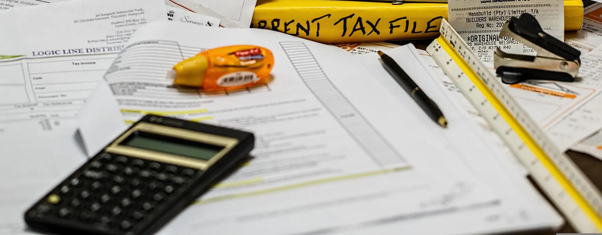 A calculator, pen and paperwork are arranged for an income-tax calculation.