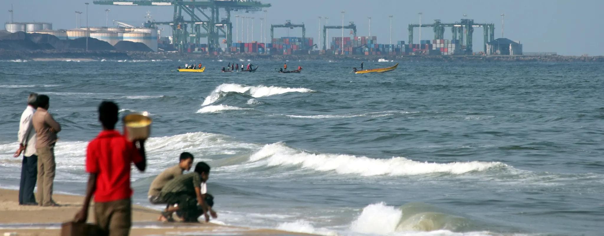 Container cranes and stacked freight at Chennai Port seen across the shoreline.